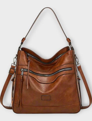 Brown hobo shoulder bag with front zipper pocket and tassel, side strap hardware