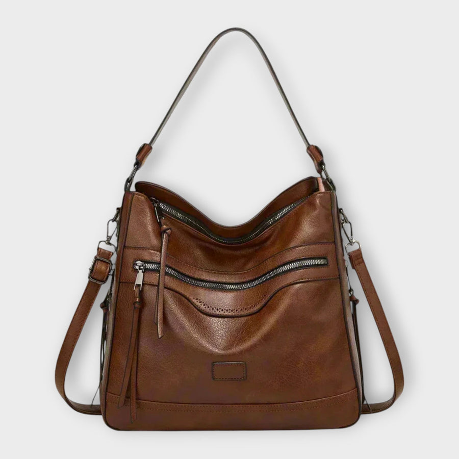 Coffee brown shoulder bag with front zip pocket and hanging tassel, adjustable straps