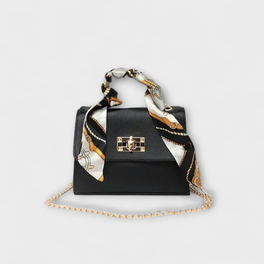 Black handbag with gold clasp, chain strap, and patterned scarf handles