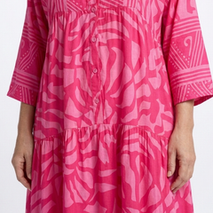 Pink button-front midi dress close-up: V-neck placket and tiered skirt, patterned.