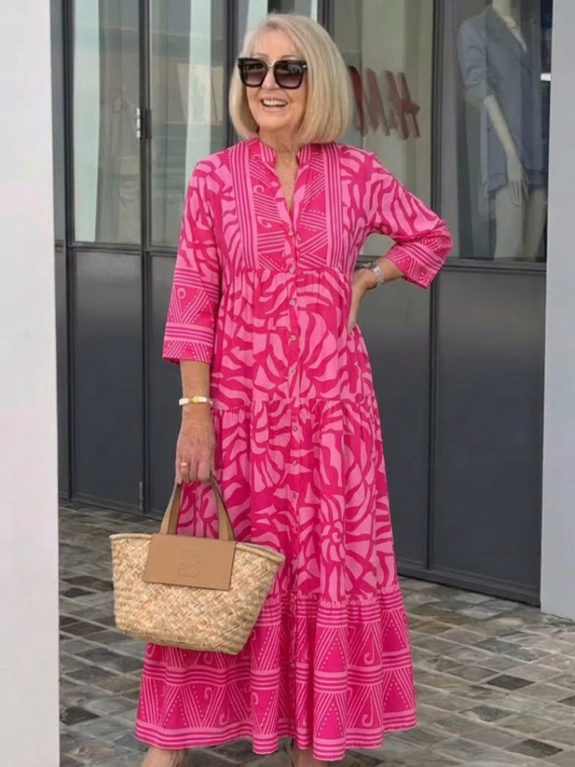 Pink button-front midi dress with V-neck and three-quarter sleeves, patterned tiered hem.