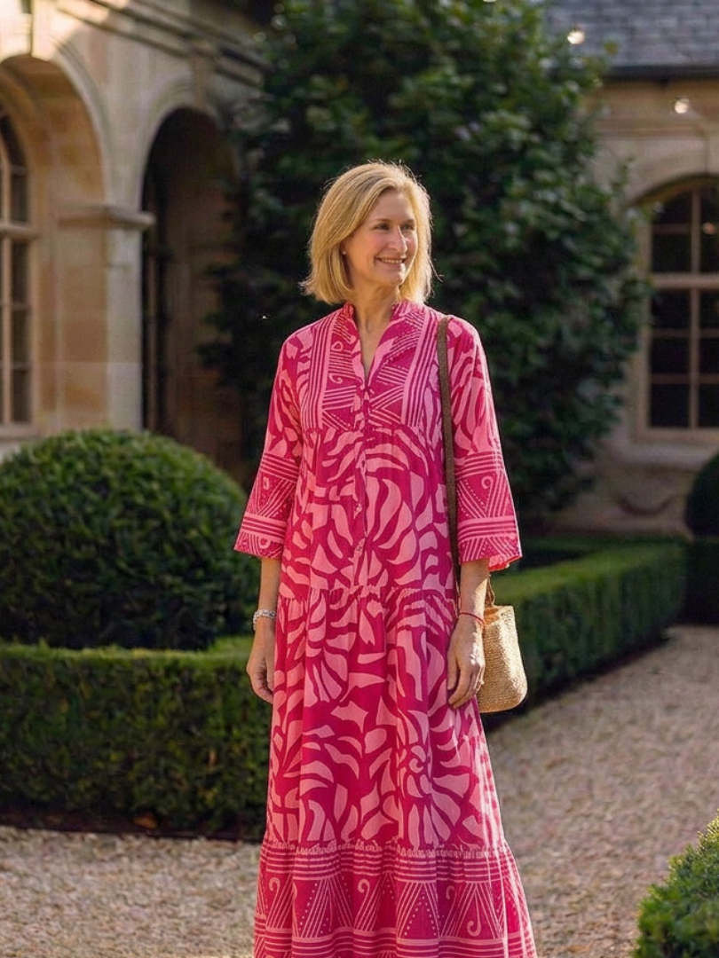 Pink button-front midi dress with V-neck and three-quarter sleeves, long tiered skirt.