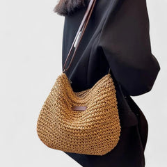 Khaki woven half-moon shoulder bag with brown leather strap and top opening