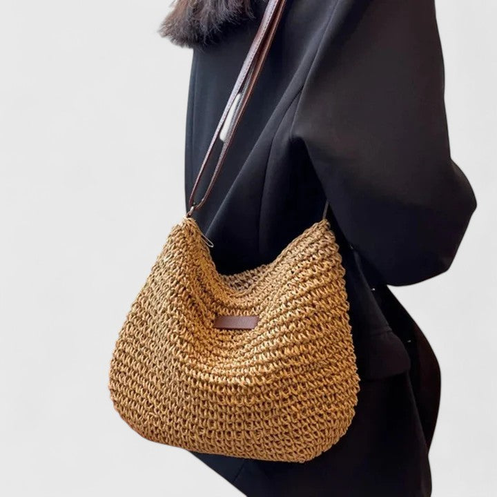 Khaki woven half-moon shoulder bag with brown leather strap and top opening