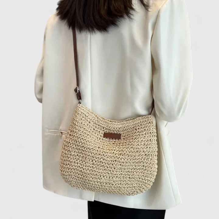 Beige woven half-moon shoulder bag with brown strap and front leather logo tab